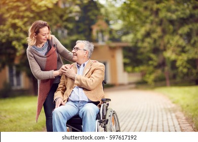 senior man in wheelchair with happy caregiver daughter