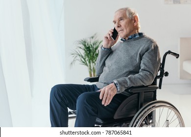 Senior Man In Wheelchair Making A Phone Call In Empty Room