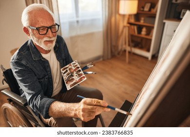 Senior man in a wheelchair painting at home