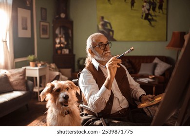 Senior man in wheelchair painting with loyal dog by his side at home - Powered by Shutterstock