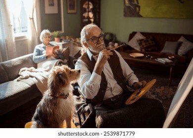 Senior man in wheelchair painting with loyal dog by his side at home - Powered by Shutterstock