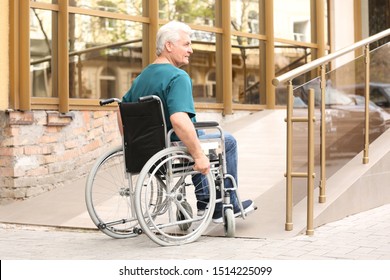 Senior Man In Wheelchair Using Ramp At Building Outdoors