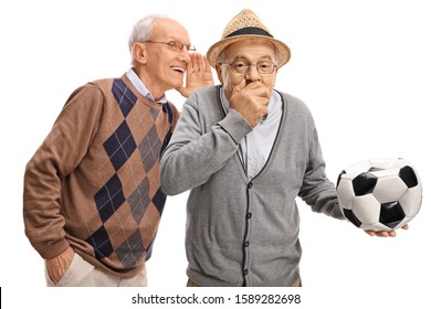 Senior Man Whispering To Friend Holding A Deflated Soccer Ball And Laughing Isolated On White Background