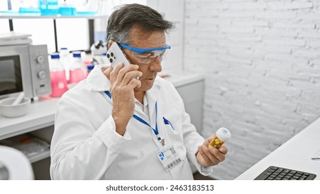 A senior man in a white lab coat examines medication while talking on the phone in a laboratory. - Powered by Shutterstock