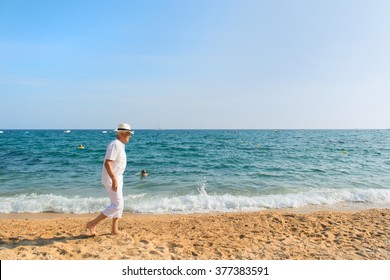 Senior man in white suit walking at the beach  - Powered by Shutterstock