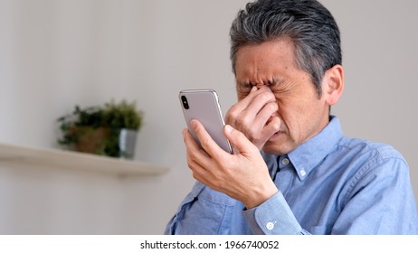 Senior Man Whose Smartphone Is Hard To See With Presbyopia