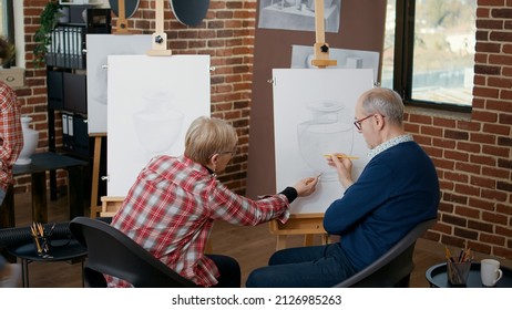 Senior Man And Woman At Community Centre Drawing Vase Model On Canvas To Develop New Skills. Old Students Attending Art Class Lesson With Teacher To Draw As New Years Resolutions.