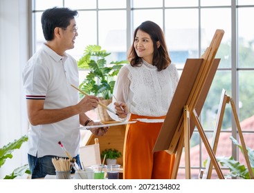 Senior Man And Woman Couple, Husband And Wife, Painting Image Together In Home Gallery With Warm And Happy Circumstance. Idea For Time-sharing And Relaxing For Older People After Retirement.