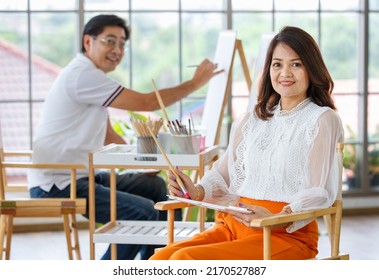 Senior Man And Woman Couple, Husband And Wife, Painting Image Together In Home Gallery With Warm And Happy Circumstance. Idea For Time-sharing And Relaxing For Older People After Retirement.