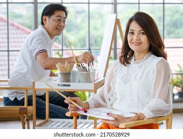 Senior Man And Woman Couple, Husband And Wife, Painting Image Together In Home Gallery With Warm And Happy Circumstance. Idea For Time-sharing And Relaxing For Older People After Retirement.