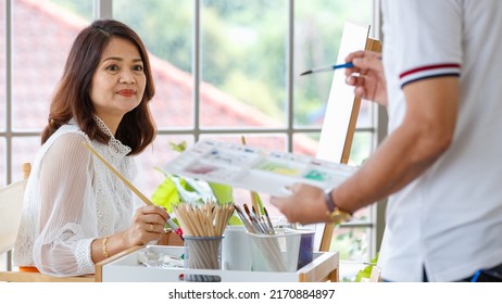 Senior Man And Woman Couple, Husband And Wife, Painting Image Together In Home Gallery With Warm And Happy Circumstance. Idea For Time-sharing And Relaxing For Older People After Retirement.