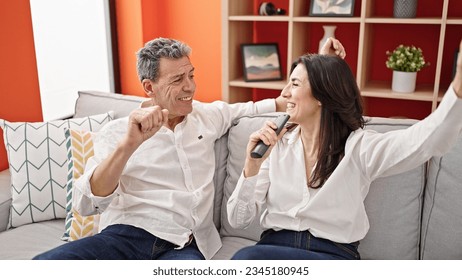 Senior man and woman couple singing song using tv remote control as a microphone at home - Shutterstock ID 2345180945