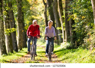 Senior Man and woman exercising with bicycles outdoors, they are a couple