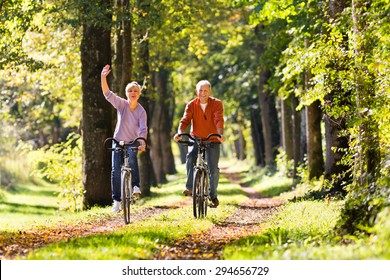 Senior Man and woman exercising with bicycles outdoors, they are a couple - Powered by Shutterstock