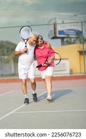 Senior man and woman hugging after playing a game of tennis at an outdoor court. - Shutterstock ID 2256076723
