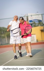 Senior man and woman hugging after playing a game of tennis at an outdoor court. - Shutterstock ID 2256076725