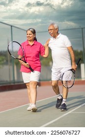 Senior man and woman hugging after playing a game of tennis at an outdoor court. - Shutterstock ID 2256076727