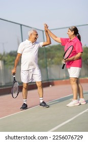 Senior man and woman hugging after playing a game of tennis at an outdoor court. - Shutterstock ID 2256076729