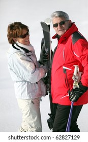 Senior Man And Senior Woman With Skis In Snow