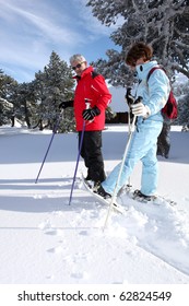 Senior Man And Woman Snowshoeing On Snow