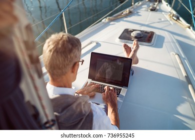 Senior man is working during the vacation on a sailboat - Powered by Shutterstock