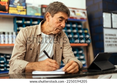 Senior man working at his hardware store. Small business concept.