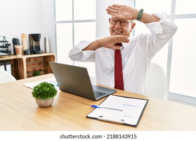 Senior Man Working At The Office Using Computer Laptop Smiling Cheerful Playing Peek A Boo With Hands Showing Face. Surprised And Exited 