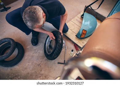 Senior Man Working On Home Hobby Project Fixing Bike Tyre