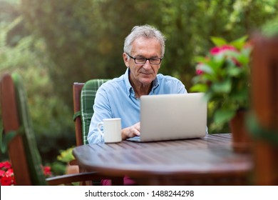 Senior Man Working On Laptop In The Garden
