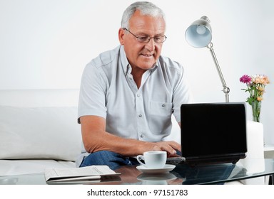 Senior Man Working On Laptop At Home