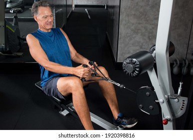 Senior Man Working Out On A Rowing Machine In The Gym