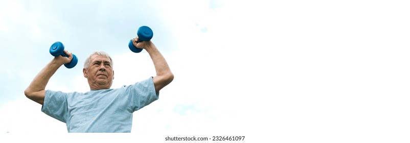 Senior man working out outdoor. Person lifting dumbbells. Old male exercising against blue sky. Healthy people lifestyle. Active sport training. Older elderly sportsman doing fitness exercise. Workout - Powered by Shutterstock