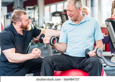 Senior Man Working Out With Personal Trainer At The Gym