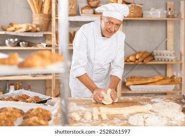 Senior man works in bakery as baker, kneads dough, works with flour. Working moment, process of creating croissants in bakery - Powered by Shutterstock