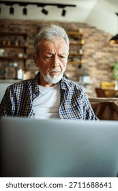 Senior man worried while using laptop at home