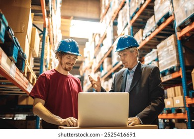 Senior manager discussing logistics with warehouse worker using laptop - Powered by Shutterstock