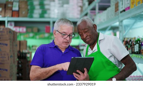 Senior Manager Presenting Tablet Screen to Senior African American Grocery Store Employee - Powered by Shutterstock