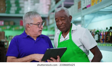 Senior Manager Presenting Tablet Screen to Senior African American Grocery Store Employee - Powered by Shutterstock