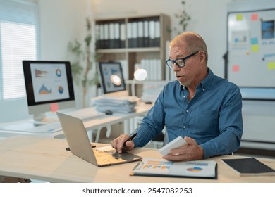 Senior manager using laptop and calculator while working with financial charts and graphs in modern office, analyzing data and preparing reports - Powered by Shutterstock