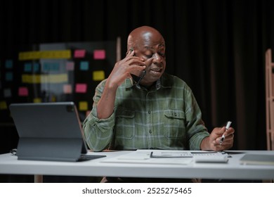 Senior manager is working late in his office, analyzing financial reports and talking on the phone - Powered by Shutterstock