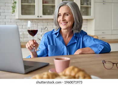 Senior Mature 60s Aged Woman Sits At Home At Table With Laptop Drinking Wine Having Virtual Video Meeting With Friends,celebrating Family Remote Video Call Party Spending Leisure Time Feeling Isolated