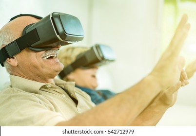 Senior mature couple having fun with virtual reality glasses - Old people using new headset goggles trends technology - New mania trends addiction - Focus on man headset - Warm greenery filtered look - Powered by Shutterstock