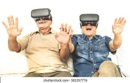 Senior mature couple having fun together with virtual reality headset sitting on sofa - Happy retired people using modern vr goggle glasses - New trends and technology concept and funny active elderly - Powered by Shutterstock