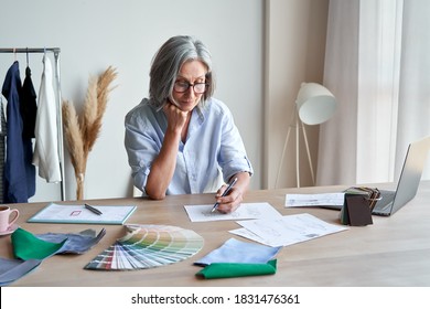 Senior Mature Elegant Female Fashion Designer Drawing Sketches In Studio Office. Middle Aged Stylish Grey-haired Older Woman Small Business Owner Creating New Fashion Design Clothes In Atelier.