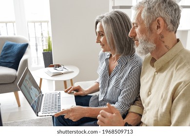 Senior Mature Family Couple Getting Online Telemedicine Call Consultation With Virtual Doctor Using Laptop Computer Sit On Couch At Home. Grandparents Ehealth, Older Patients Telehealth Consultation.