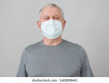 Senior in medical mask isolated on gray background. Studio portrait of adult man looking at camera Flu epidemic, dust allergy, protection against virus. Covid-19, coronavirus pandemic
