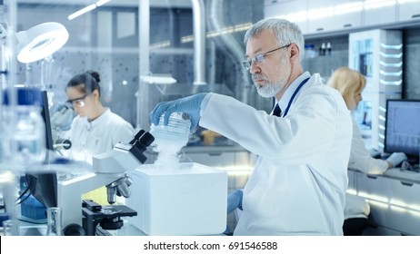 Senior Medical Research Scientist Takes Out Petri Dish with Samples from Opened Refrigerator Box. He Works in a Busy Modern Laboratory Center. - Powered by Shutterstock