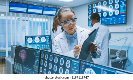 Senior Medical Scientist Consults Female Apprentice With Clipboard, He Works With CT Brain Scan Images On A Personal Computer In Laboratory. Neurologists In Research Center Work On Brain Tumor Cure.