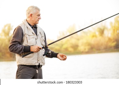 Senior Men Fishing By The Lake.