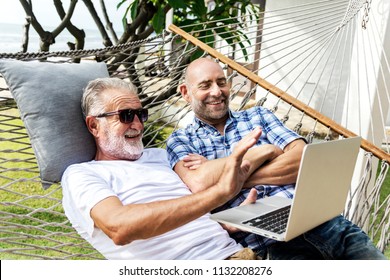 Senior men lying on a hammock using a laptop - Powered by Shutterstock